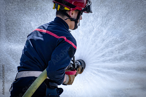 Fotografie jeune pompier Français qui tient une lance à incendie lors d'un exercice