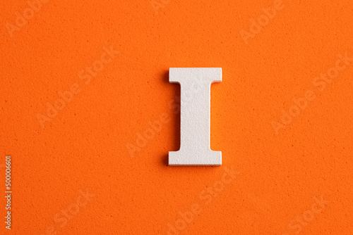 Alphabet letter I - White wood piece on orange foamy background