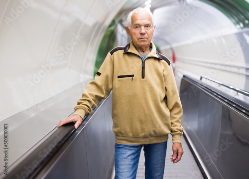 Old man standing on travolator photo