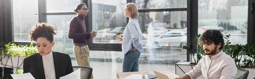 Obraz premium Multiethnic business people working near blurred colleagues in office, banner.