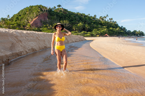 Fit women in a yellow bikini at the beach known as Pitinga, in Arraial d’ Ajuda, Bahia, Brazil  photo