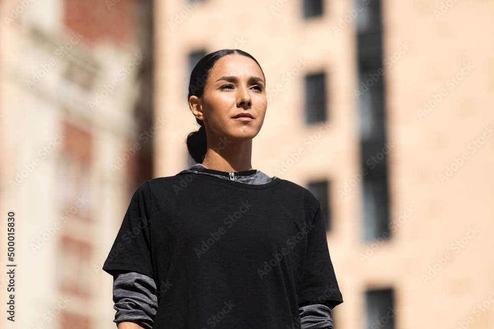Fototapeta premium Portrait of serious confident pretty millennial arabic woman athlete in sportswear looks towards empty space