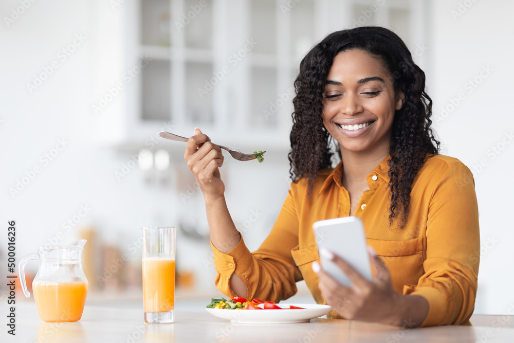 Happy black woman surfing on social media while having breakfast Happy black woman surfing on social media while having breakfast