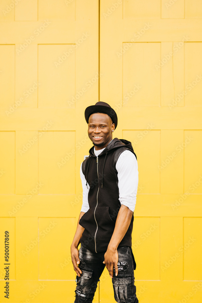 Portrait of a young smiling black male standing against a yellow door Portrait of a young smiling black male standing against a yellow door