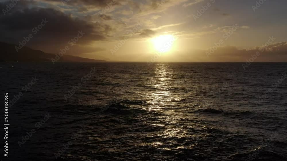 Drone flying low over the ocean towards the sun at sunset Drone flying low over the ocean towards the sun at sunset