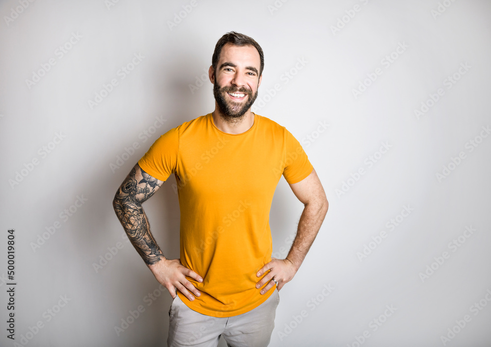 portrait of casual young man with beard and tattoo and Burnt Orange shirt on white background portrait of casual young man with beard and tattoo and Burnt Orange shirt on white background
