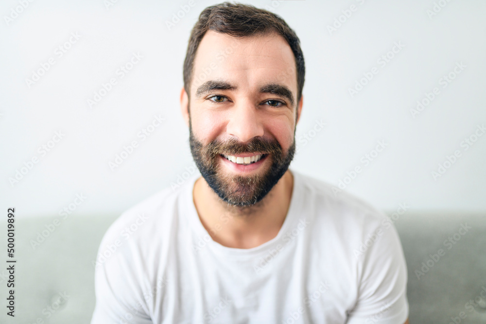 portrait of casual young man with beard on sofa at home portrait of casual young man with beard on sofa at home