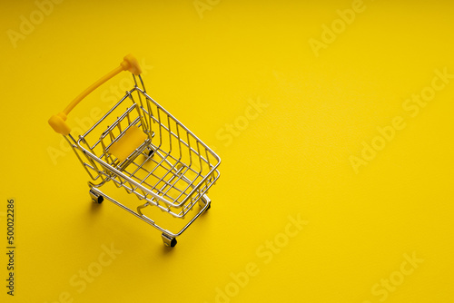 Shopping cart on yellow background with copy space. Shopping concept
