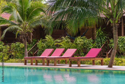 Swimming pool with relaxing beds and green palm trees in tropical garden , Thailand © OlegD