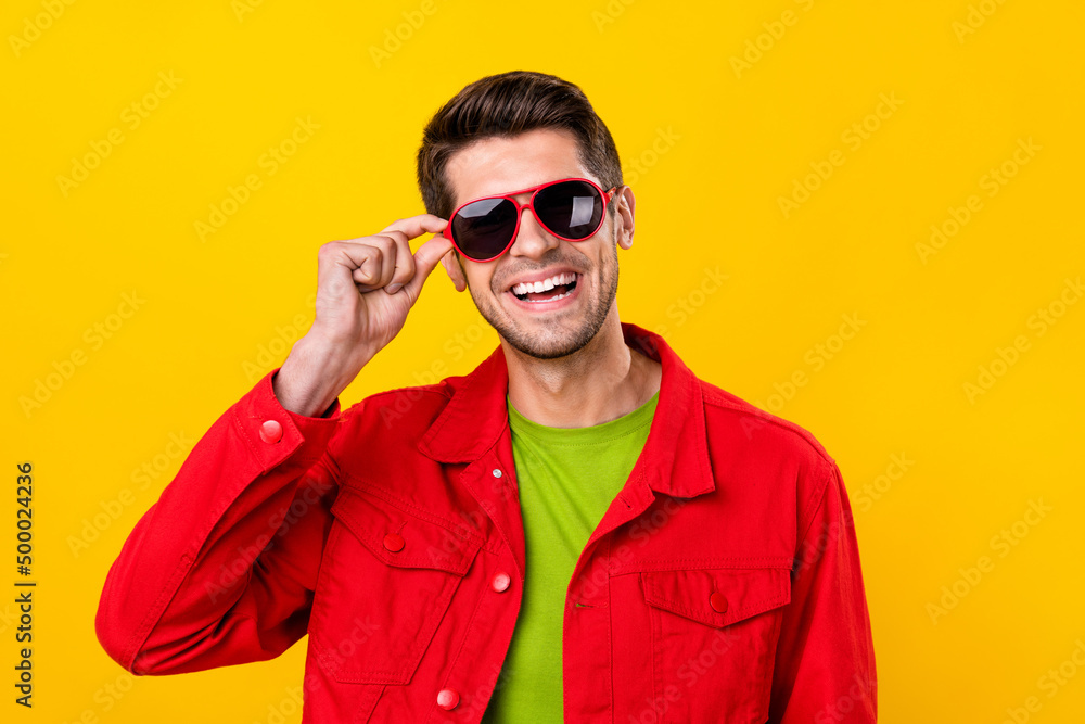 Portrait of attractive cheerful guy touching specs good mood isolated over vibrant yellow color background Portrait of attractive cheerful guy touching specs good mood isolated over vibrant yellow color background