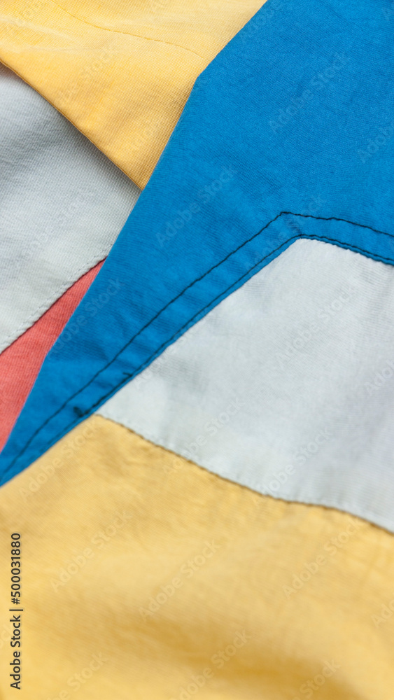 Detalle de chándal de polyester de colores azul, blanco, amarillo y rosa Detalle de chándal de polyester de colores azul, blanco, amarillo y rosa