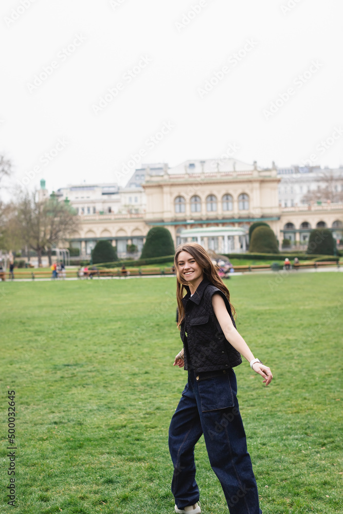 Fototapeta premium young joyful woman in sleeveless jacket in green park.