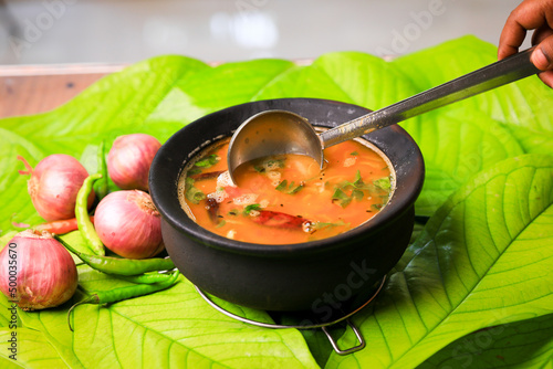 south indian famous rasam,sambar served in a traditional mud pot closeup with selective focus and bl photo