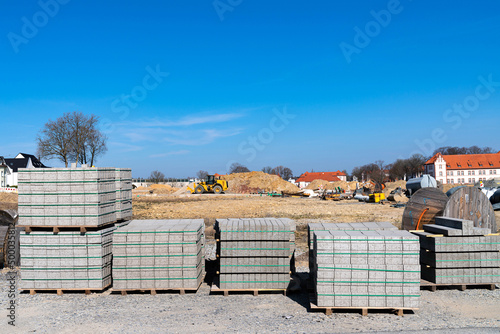 Road tiles on wooden pallets. Construction site with machinery and building materials. Sonny day.