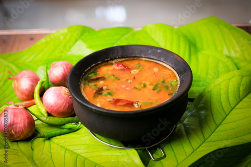 south indian famous rasam,sambar served in a traditional mud pot closeup with selective focus and bl photo