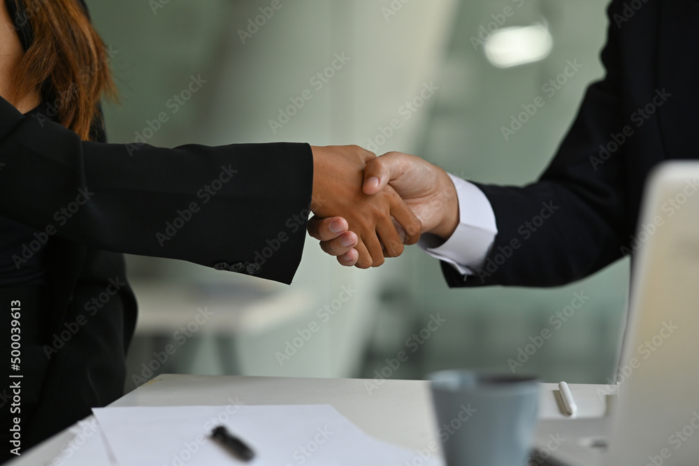 Close up businesspeople hands doing a handshake in a workplace, for business and technology concept. Close up businesspeople hands doing a handshake in a workplace, for business and technology concept.