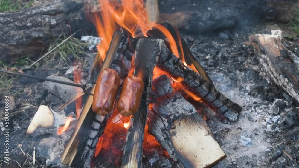 BBQ roasting of sausages wursts on stick at outside campfire open fire BBQ roasting of sausages wursts on stick at outside campfire open fire