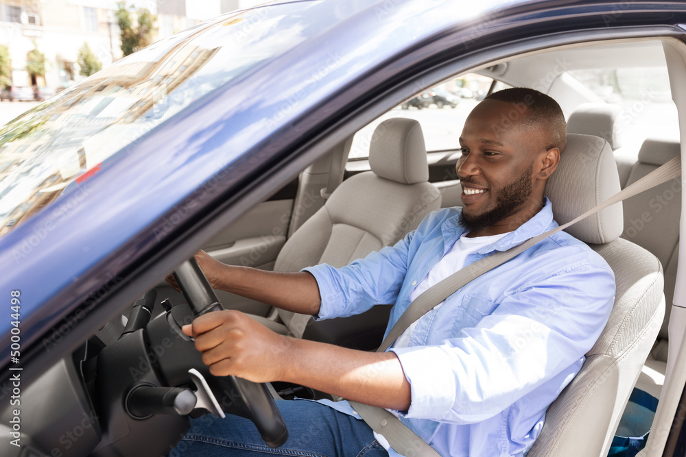Smiling black guy driving new car in city Smiling black guy driving new car in city