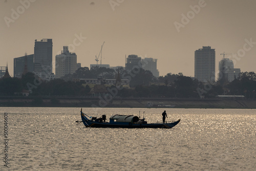 Silhouette of a fisherman on Tonle Sap Mekong junction in front of Sokha Phnom Penh at dusty sunset photo