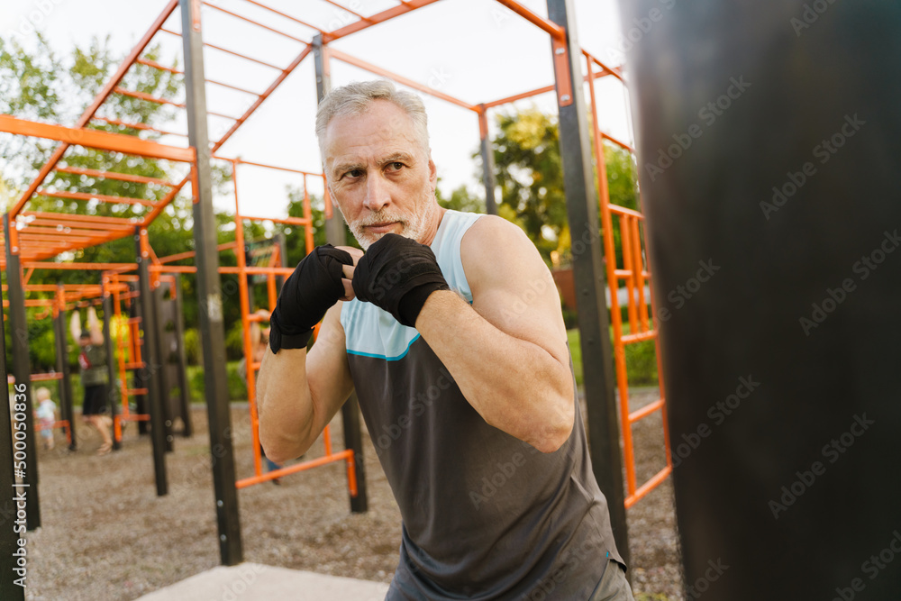 Obraz premium Gray mature man boxing while working out on playground