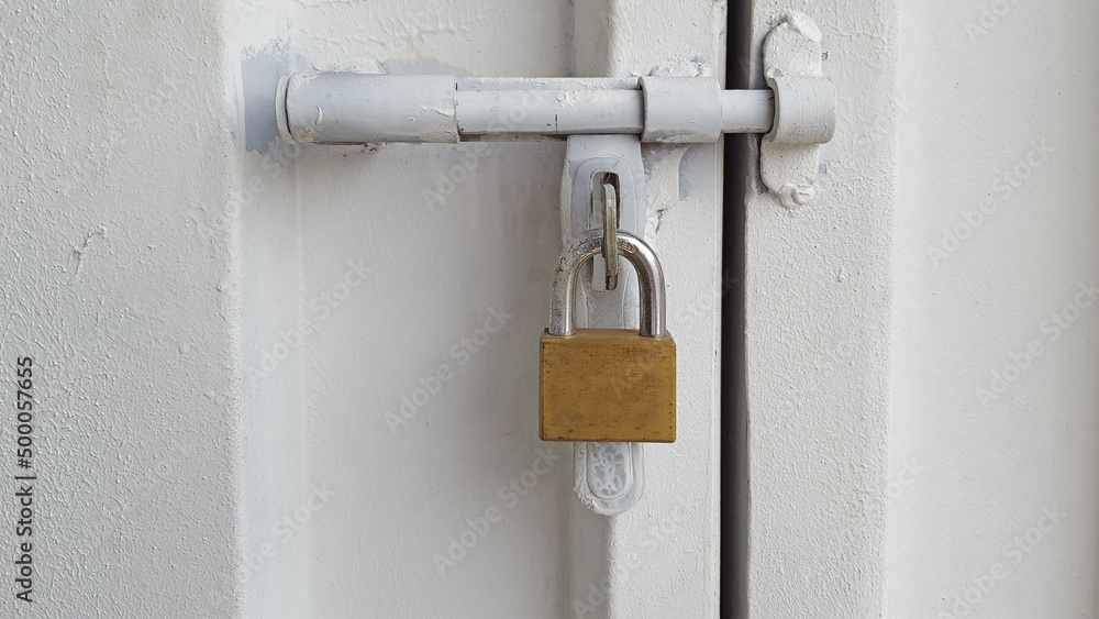 The white iron door is locked with a large padlock.