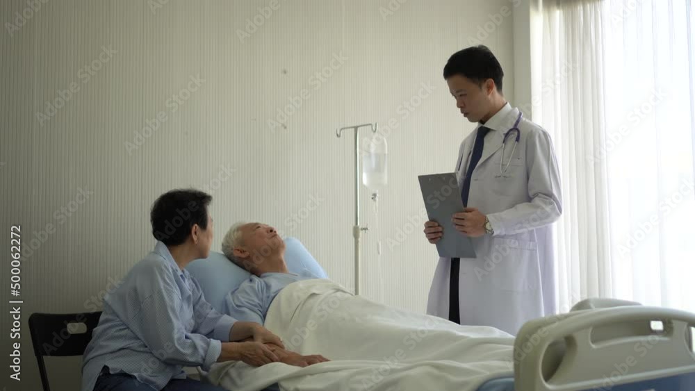 Asian young man doctor giving advice on senior old patient at recovery hospital room Asian young man doctor giving advice on senior old patient at recovery hospital room