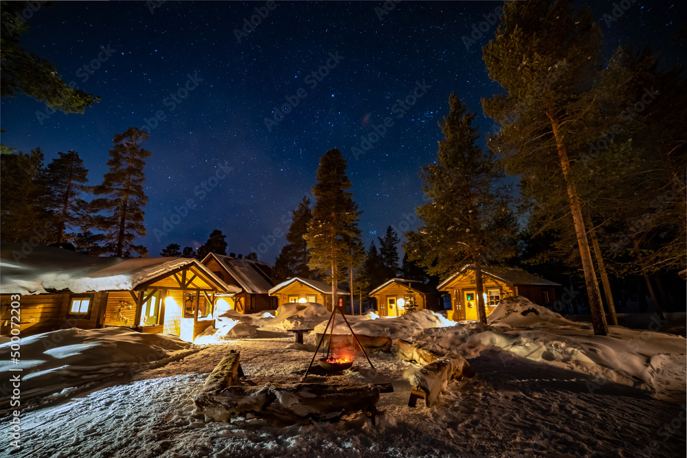 Fototapeta premium Northern Lights in the arctic winter with snow and chalets