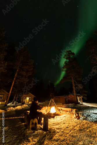 Northern Lights in the arctic winter with snow and chalets