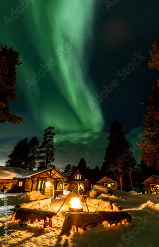 Northern Lights in the arctic winter with snow and chalets