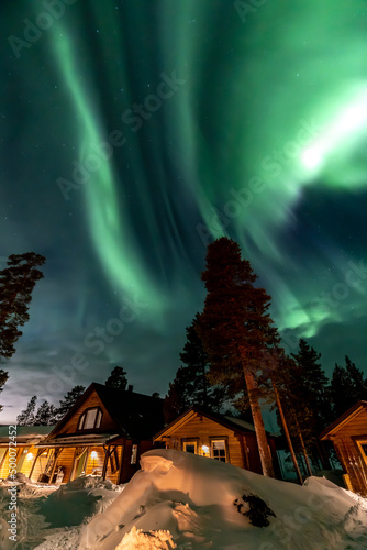 Northern Lights in the arctic winter with snow and chalets