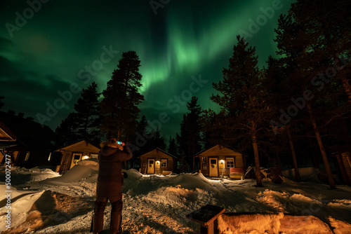 Northern Lights in the arctic winter with snow and chalets