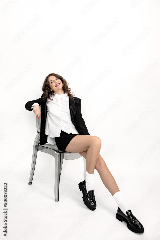Gorgeous business woman posing in studio, looking at the camera, smiling. Beautiful young lady in stylish wear sit on the chair, smiling. Pretty female shows success and self confidence Gorgeous business woman posing in studio, looking at the camera, smiling. Beautiful young lady in stylish wear sit on the chair, smiling. Pretty female shows success and self confidence