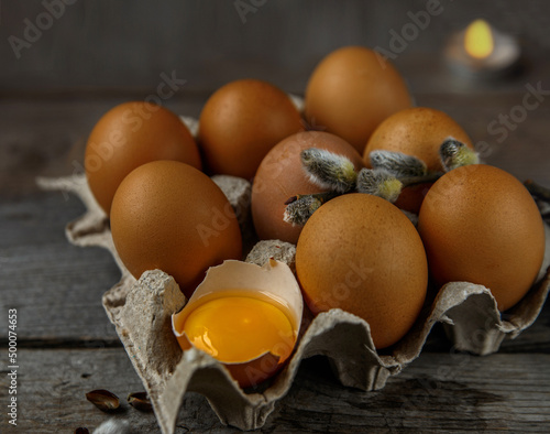 Paper box with chicken eggs and branch of willow. One egg broken