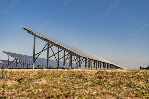 Many solar panels in northern Poland, providing energy to surrounding houses. Solar energy farm made of many panels in rows. Clear sky with no clouds and sunny weather. © Gosia