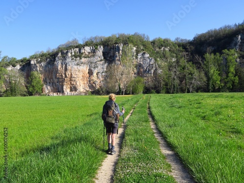 Fototapeta randonneur randonneuse femme marchant dans pré sur un sentier vers des falaises