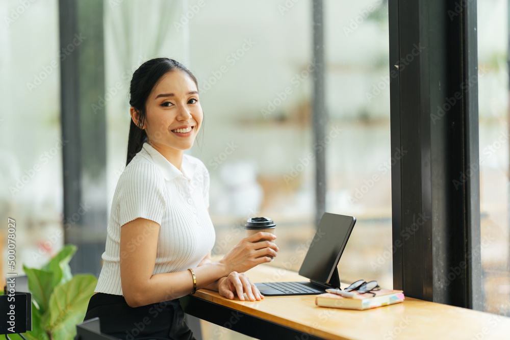 Beautiful young asian business woman drinking coffee and using laptop computer while working in office. Beautiful young asian business woman drinking coffee and using laptop computer while working in office.