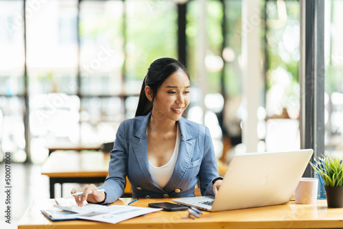 Portrait of Asian young female working on laptop at office, financial and investment concept.