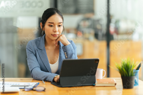 Portrait of Asian young female working on laptop at office, business financial and investment concept.