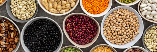 Banner of different types of legumes in bowls, green with yellow peas and mung beans, chickpeas and peanuts, colored beans and lentils, top view