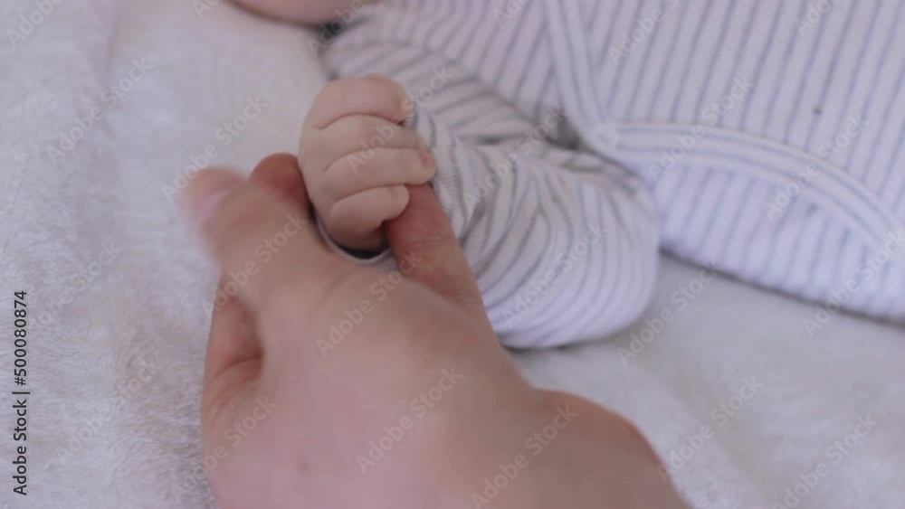 Baby infant newborn white hands touching with male adult hands, reaching father's hand, parent holding, static closeup Baby infant newborn white hands touching with male adult hands, reaching father's hand, parent holding, static closeup