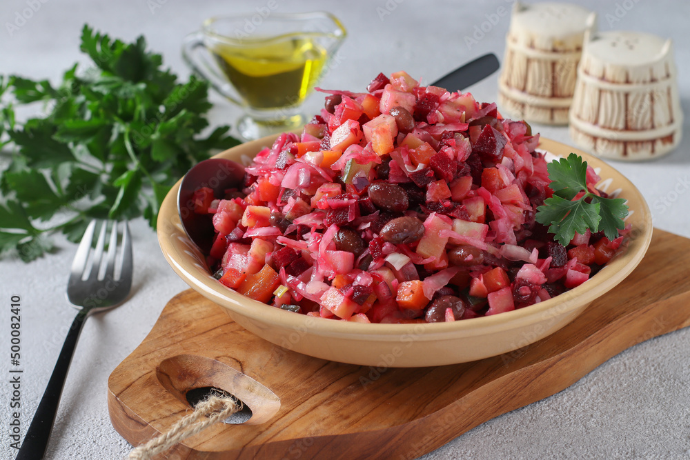 Traditional Salad Vinaigrette with beans, pickles, pickled cabbage and boiled vegetables in clay plate on wooden board, Close-up Traditional Salad Vinaigrette with beans, pickles, pickled cabbage and boiled vegetables in clay plate on wooden board, Close-up