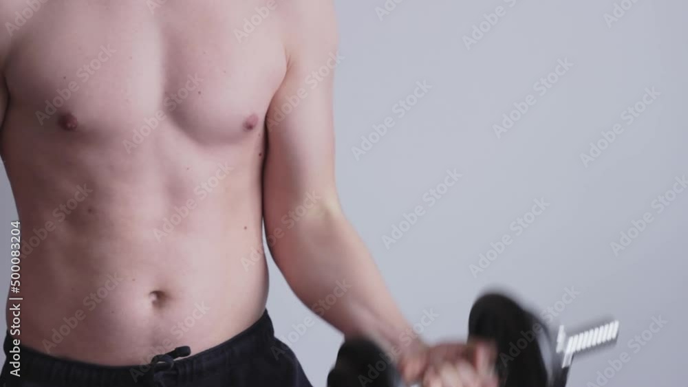 Medium closeup of shirtless man weight exercising biceps, static interior Medium closeup of shirtless man weight exercising biceps, static interior