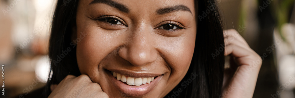 Black young woman smiling and looking at camera indoors Black young woman smiling and looking at camera indoors