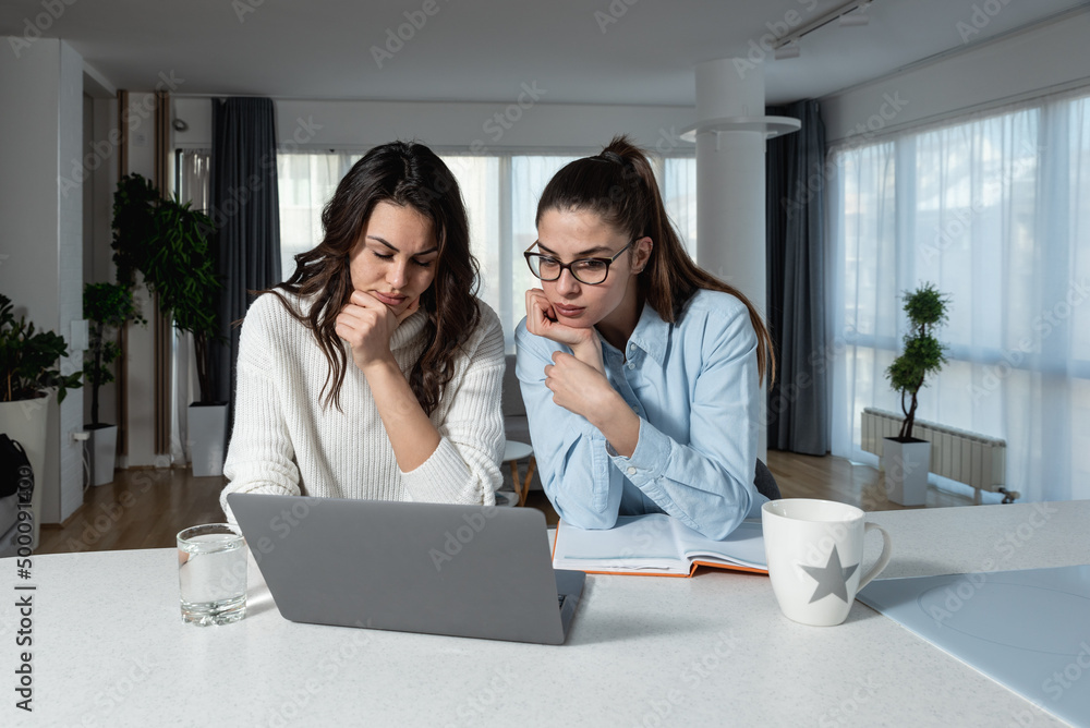 Two young business females freelancer colleagues discuss job chat hold  pleasant conversation at home office workplace. Young woman project manager  assist coworker explain work in corporate app Photos | Adobe Stock