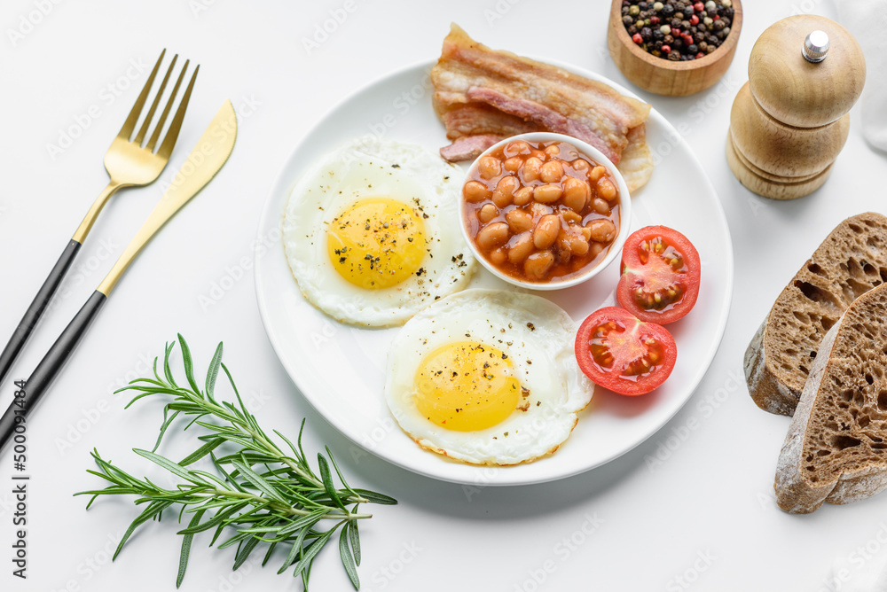 English breakfast with fried eggs, bacon, beans, tomatoes, spices and herbs English breakfast with fried eggs, bacon, beans, tomatoes, spices and herbs