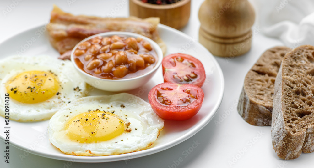 English breakfast with fried eggs, bacon, beans, tomatoes, spices and herbs English breakfast with fried eggs, bacon, beans, tomatoes, spices and herbs
