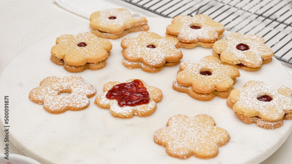 Flower shaped shortbread cookies filled with raspberry jam step by step recipe. Spreading a layer of raspberry jam on baked cookies