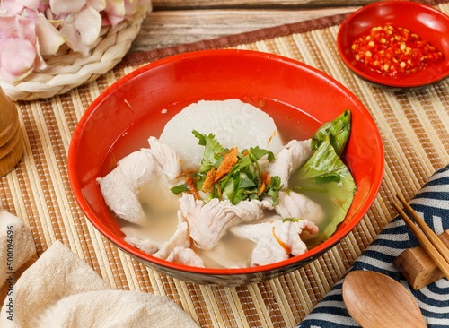 sliced ​​meat soup in a bowl with spoon and chopsticks isolated on mat side view on wooden table taiwan food
