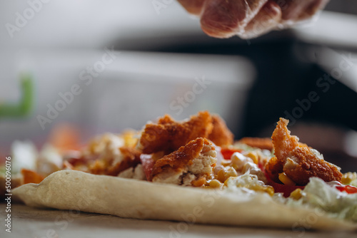 Men's hands wrapping traditional shawarma wrap with chicken and vegetables photo