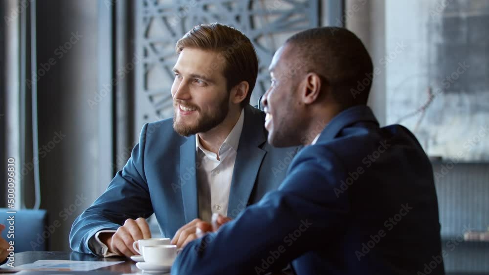 Two laughing businessmen in suits at a meeting in a loft Two laughing businessmen in suits at a meeting in a loft